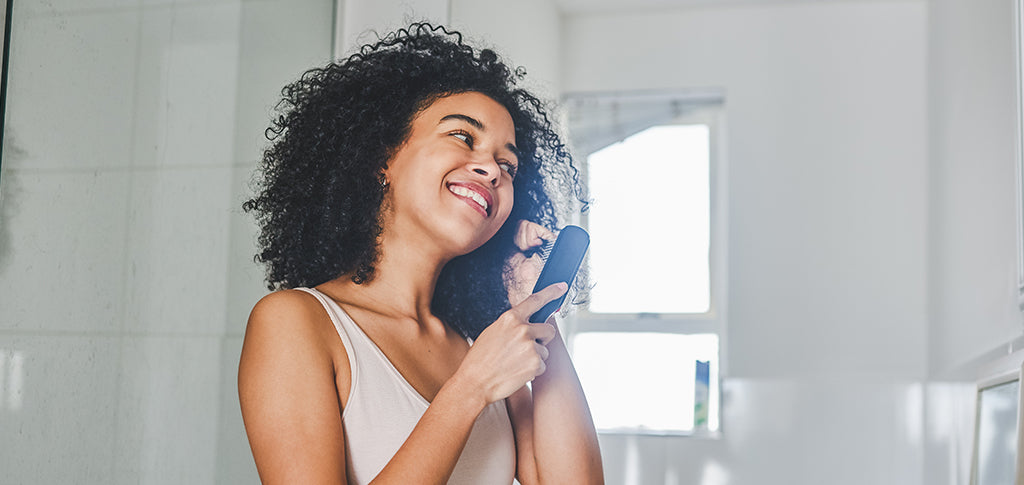 Image of Woman brushing her curly hair
