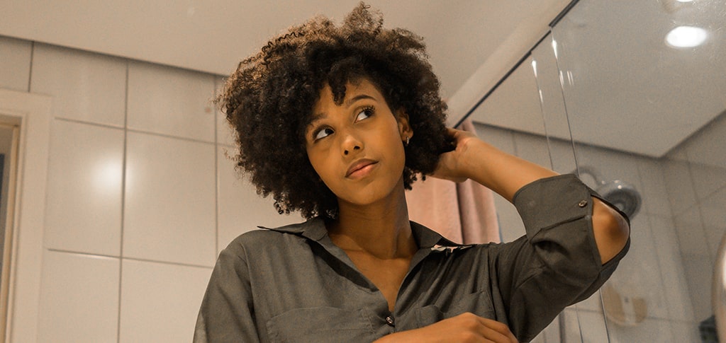 Image of Woman touching her hair in the bathroom
