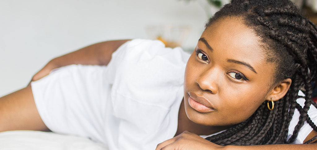 Image of Young African Woman Lying Down On A White Bed