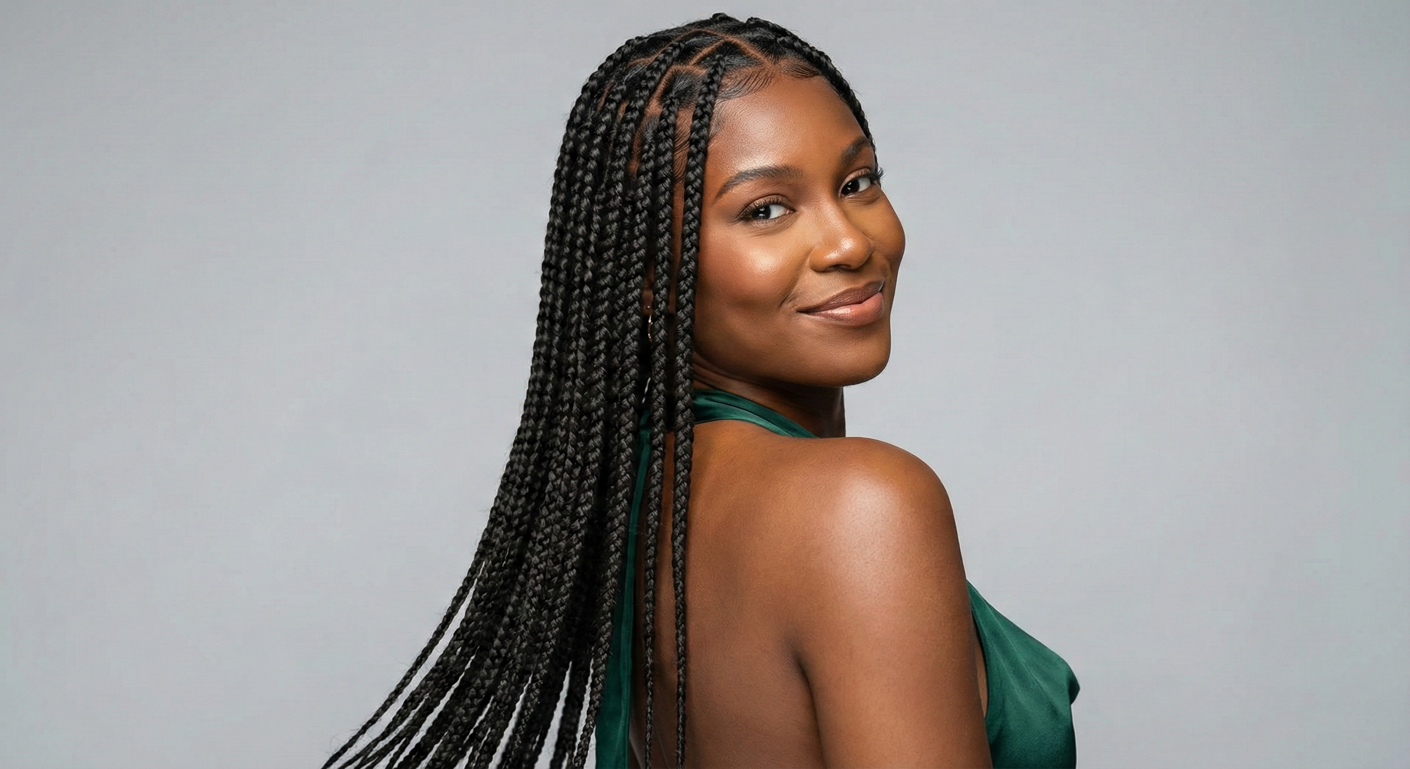 Woman with braided hair wearing a green top against a gray background